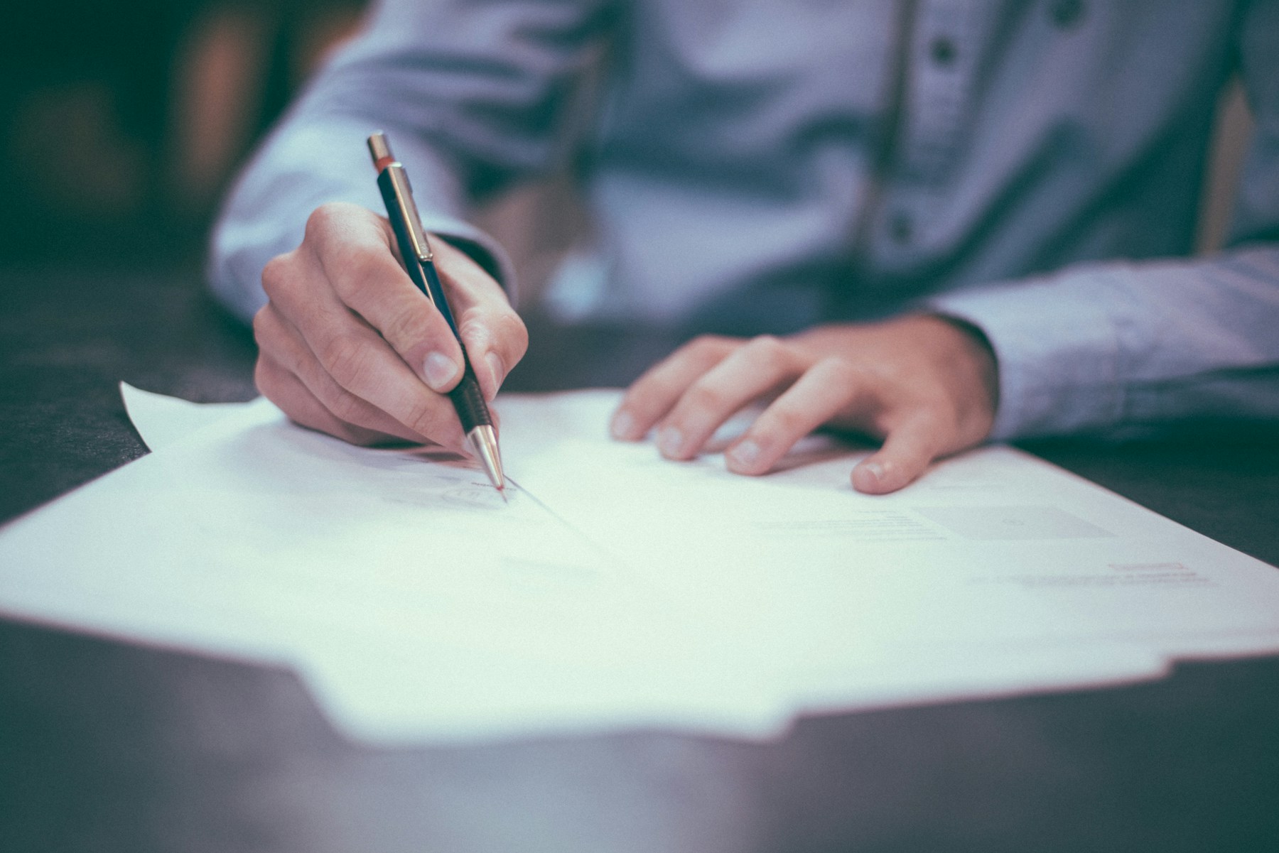 An adviser reviewing and signing paperwork at a desk